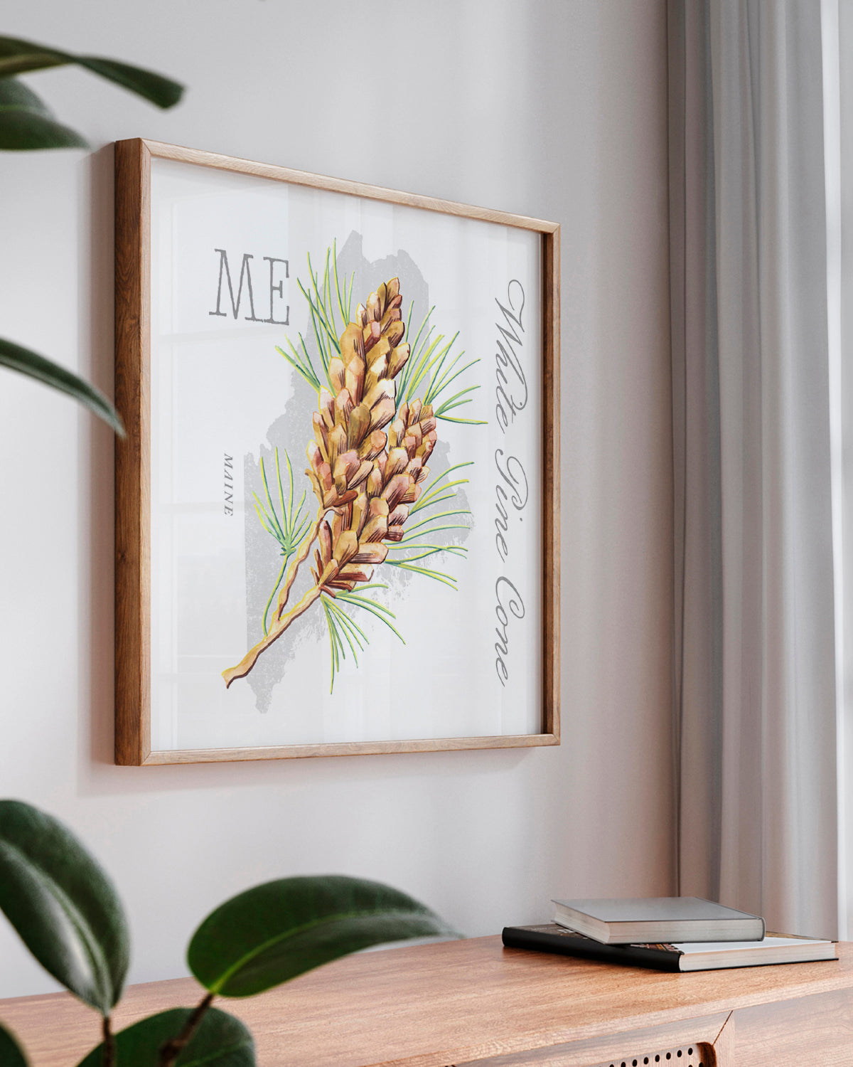Framed Maine state flower botanical wall art by Jen Montgomery hanging on a light gray wall above a wooden console table.