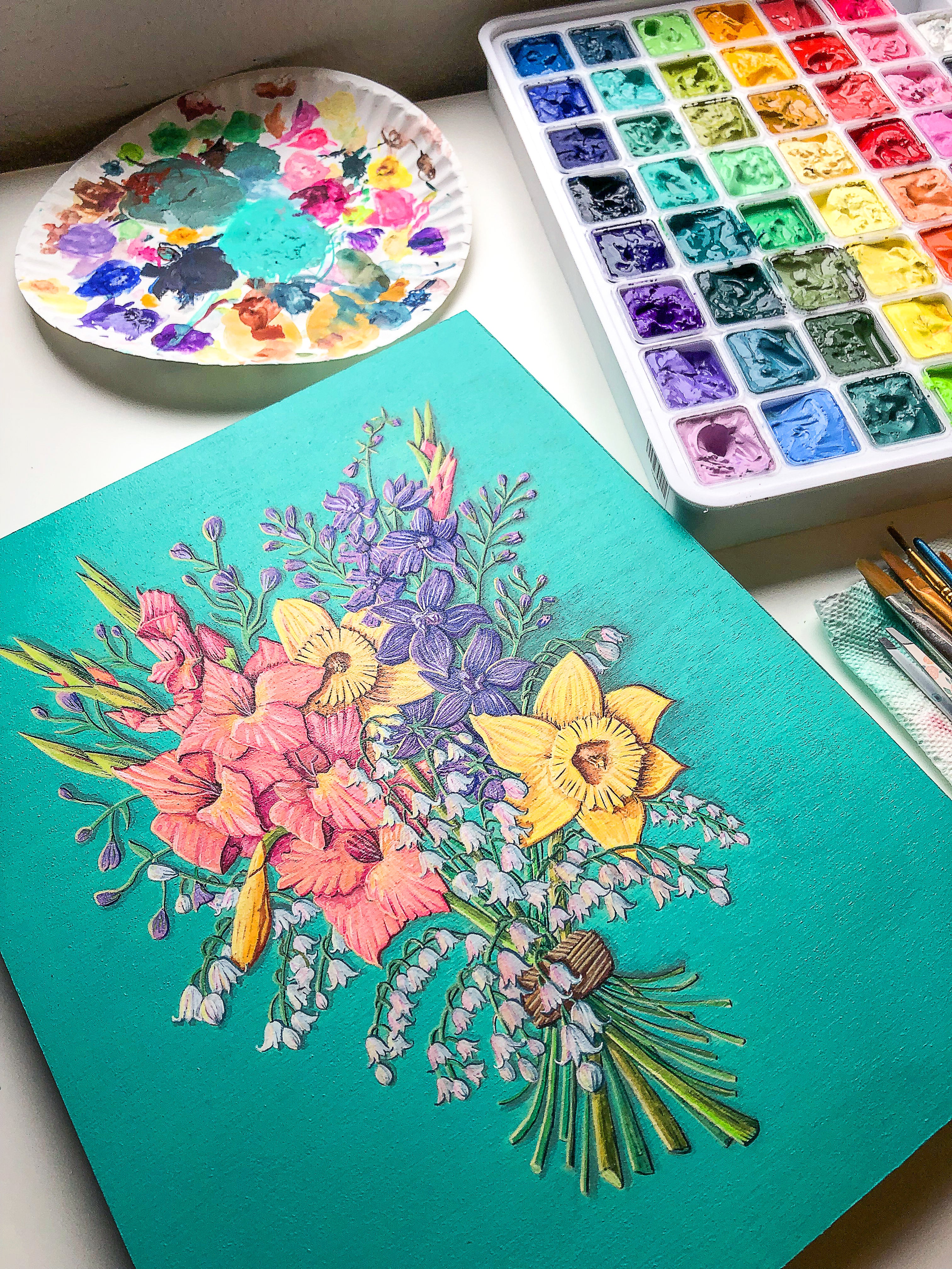 Colorful floral painting on a teal background with watercolor palette and brushes. Artwork by Jen Momntgomery.