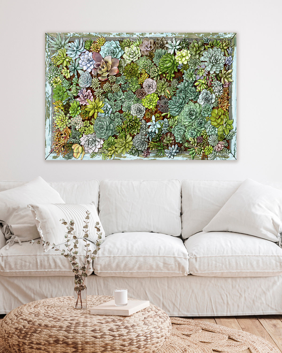 Framed succulent living wall art by Jen Montgomery on a wall above a white sofa in a living room.