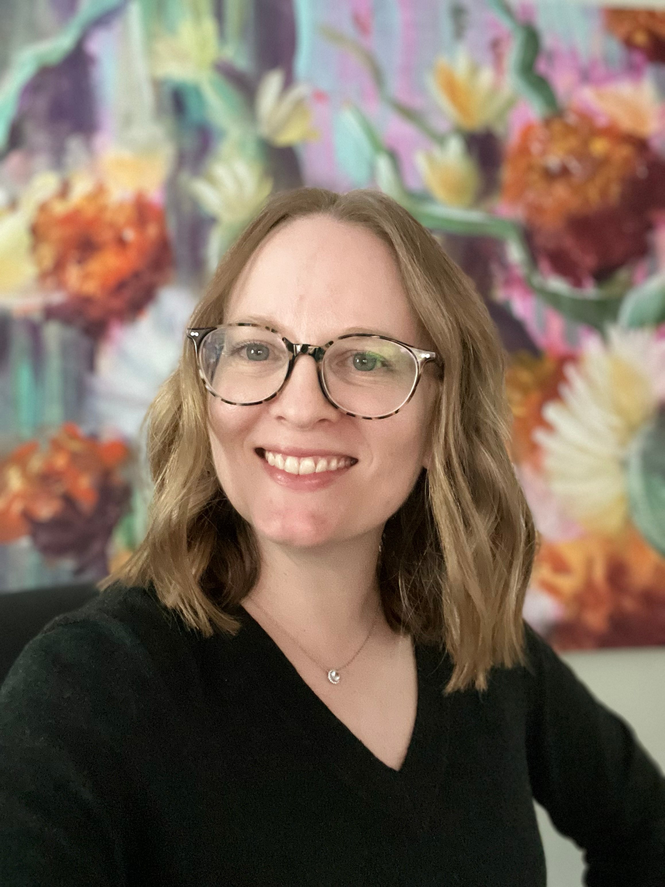 Jen Montgomery in front of her colorful floral painting